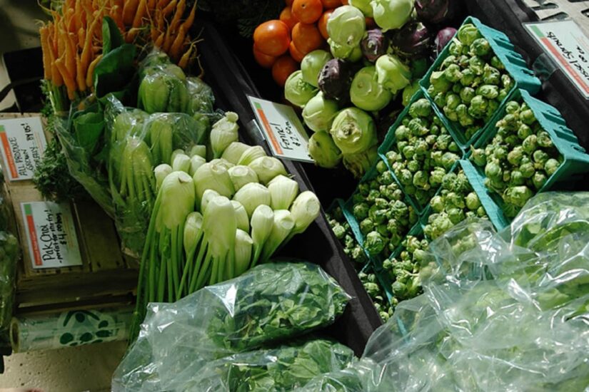 An assortment of fresh vegetables – bunches of carrots, leafy greens, onions, and Brussels