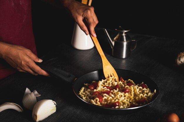 Man cooking pasta in a frying pan