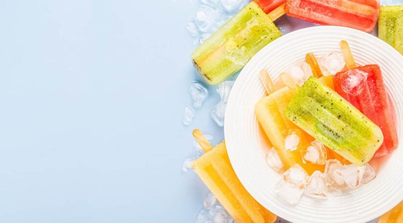 Assorted fruit popsicles on a white plate with ice cubes