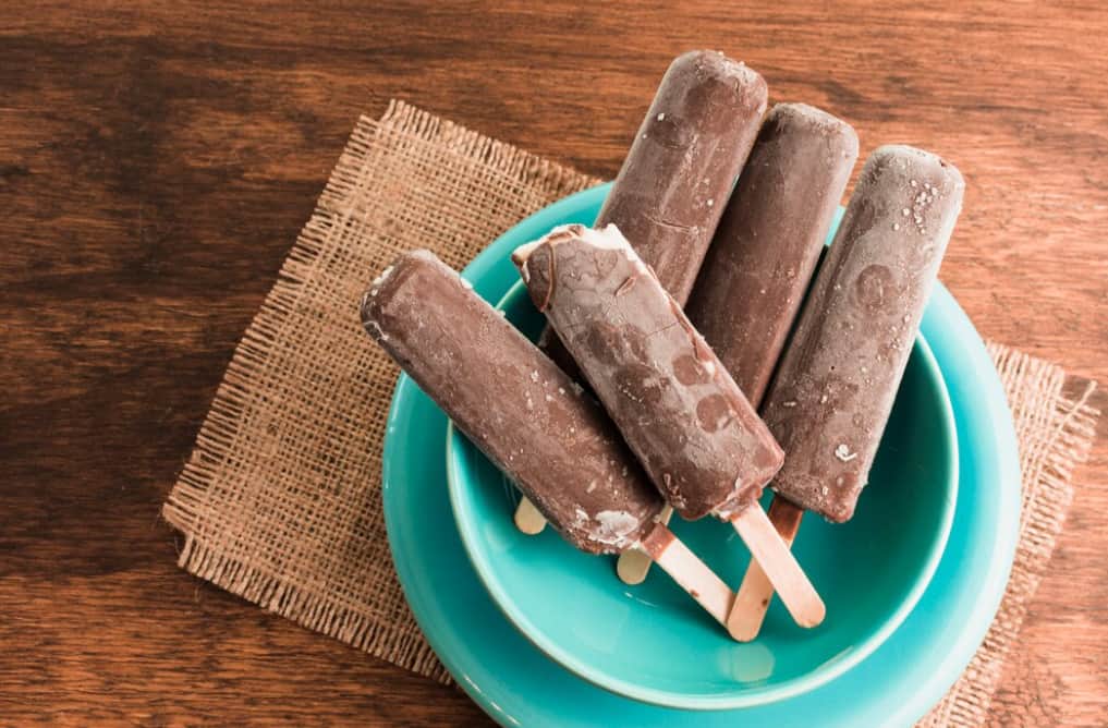 Chocolate popsicles on a blue plate with a burlap cloth