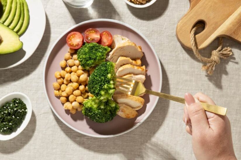 A healthy plate with chicken, chickpeas, broccoli, and tomatoes