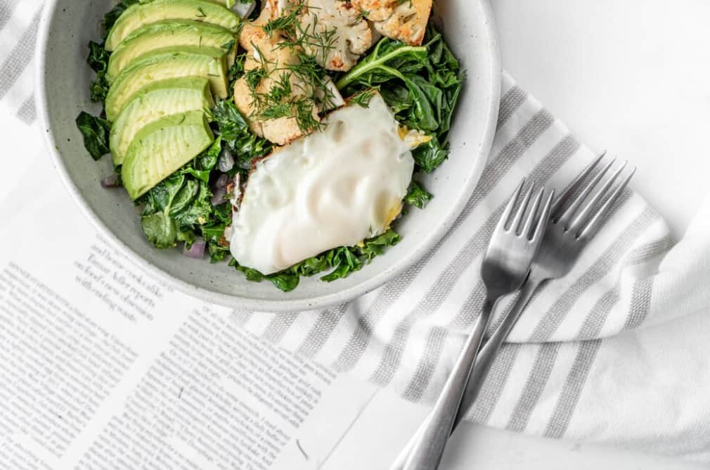 A bowl with avocado, chicken, greens, and a poached egg