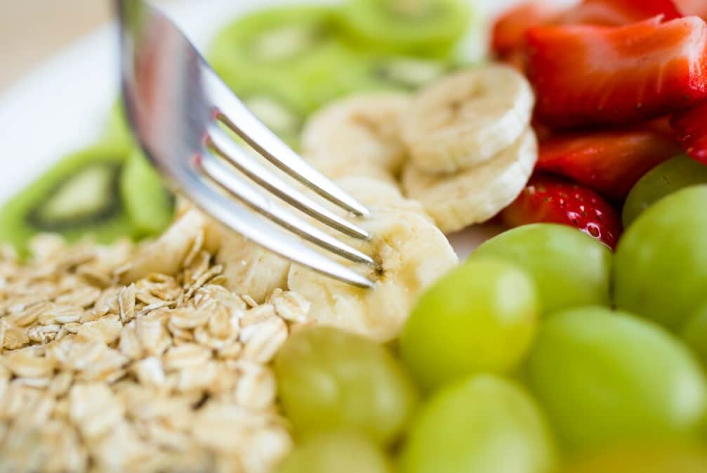 A fresh fruit salad with oats, banana, kiwi, and berries