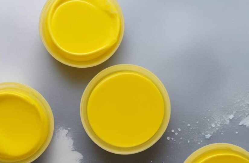 pen jars of bright yellow beeswax balm on a grey surface