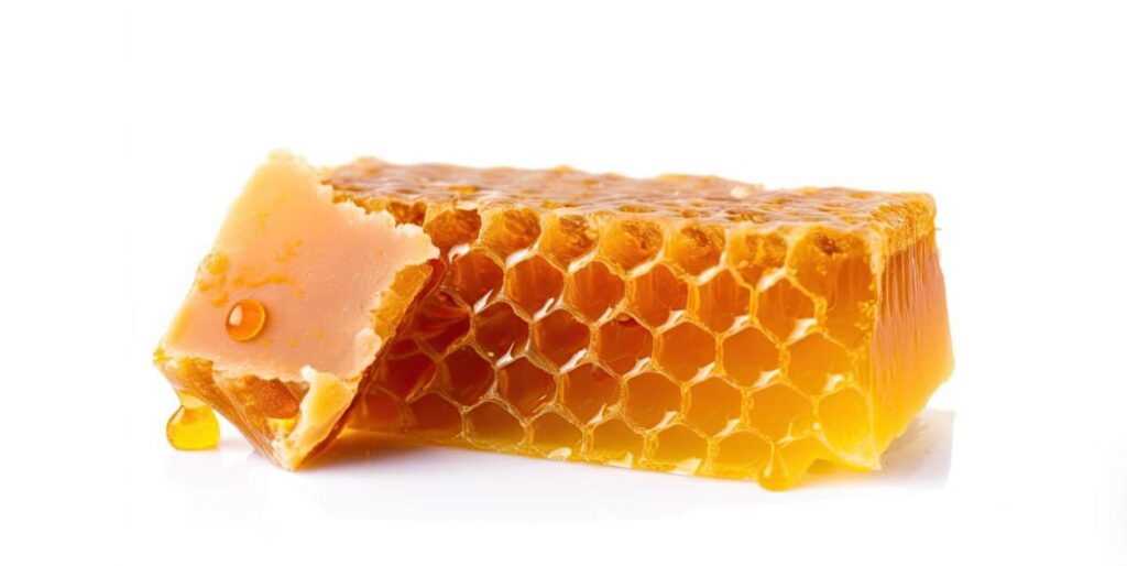 A piece of honeycomb with dripping honey on a white background