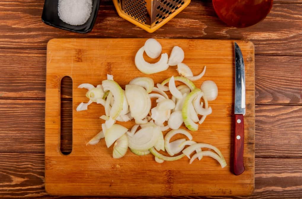 Chopped onions on a cutting board with a knife and salt