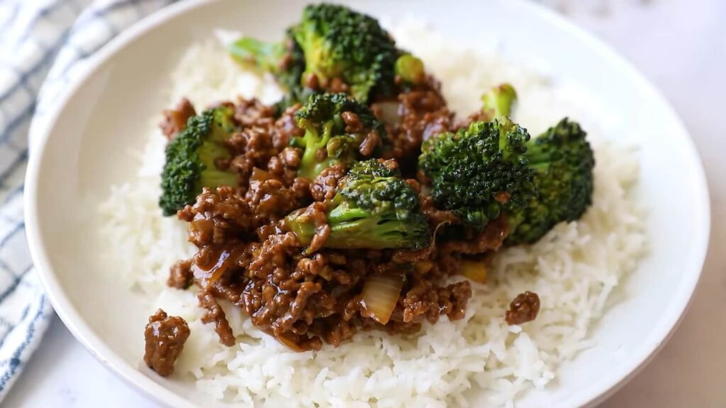 Close-up of beef broccoli stir fry served over fluffy white rice in a bowl