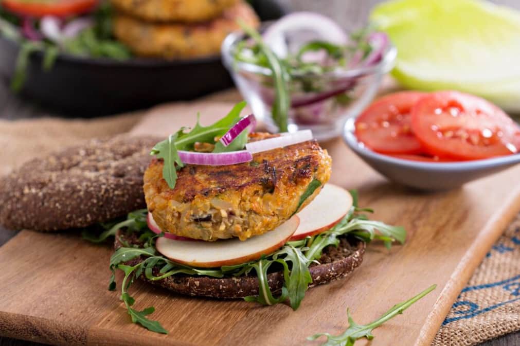 Open-faced mung bean burger on a rustic bread with fresh greens