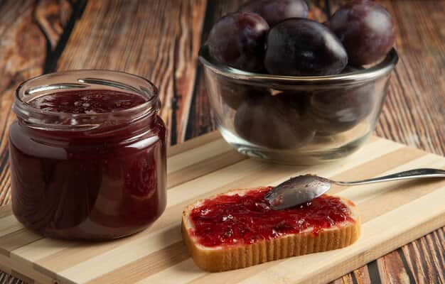 Plums with a jar of jam and croutons
